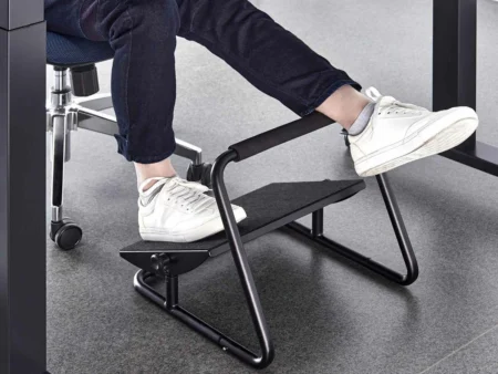 Person resting feet on Furnotix ergonomic footrest with padded leg bar under desk.